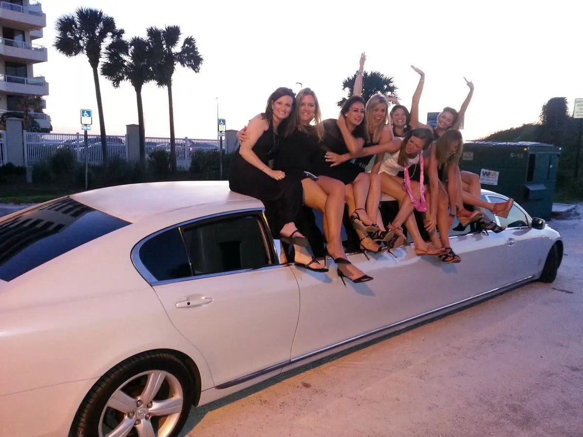Group posing beside a white stretch limousine
