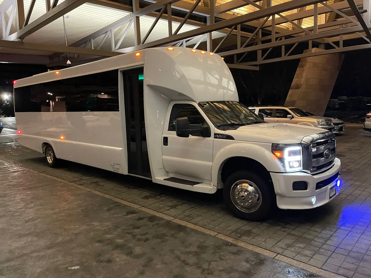 White party bus exterior at night with interior lights on
